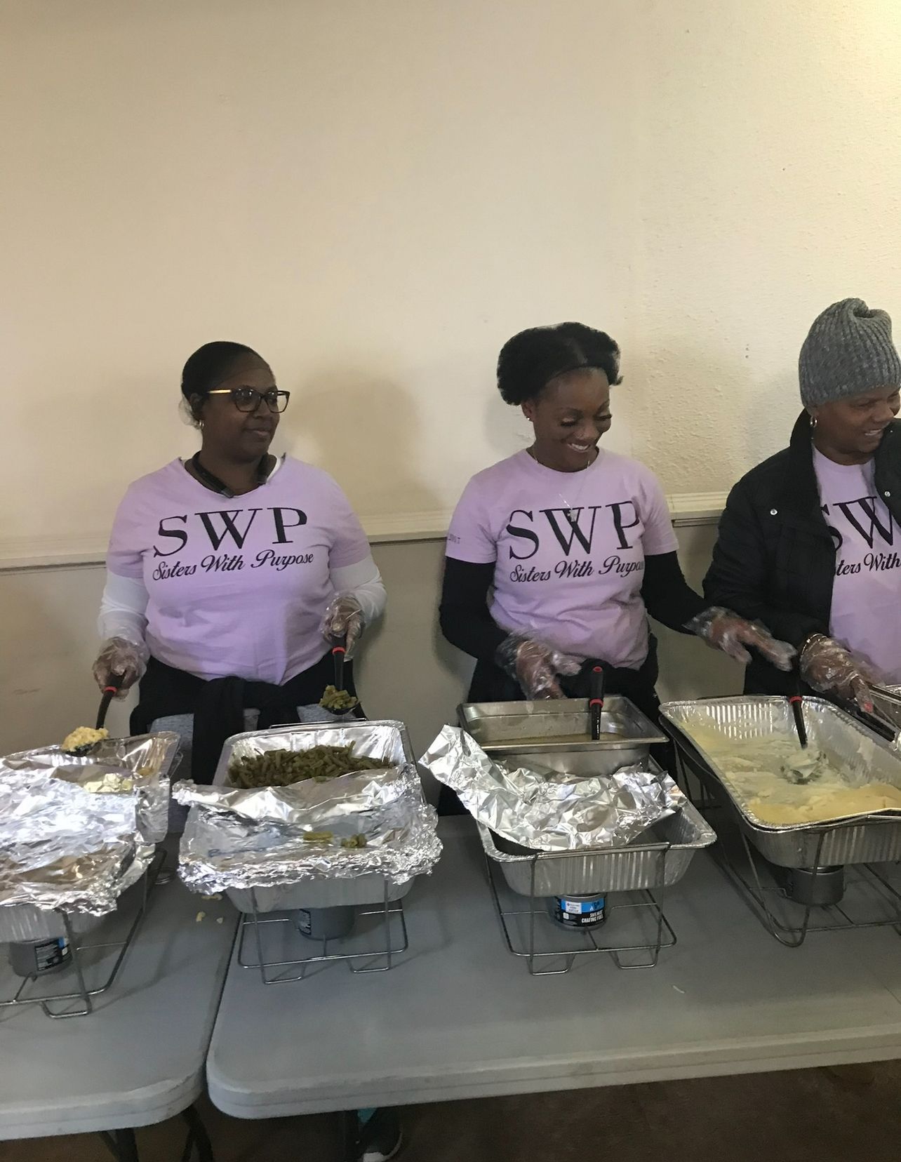 A group of people are standing around a table serving food.