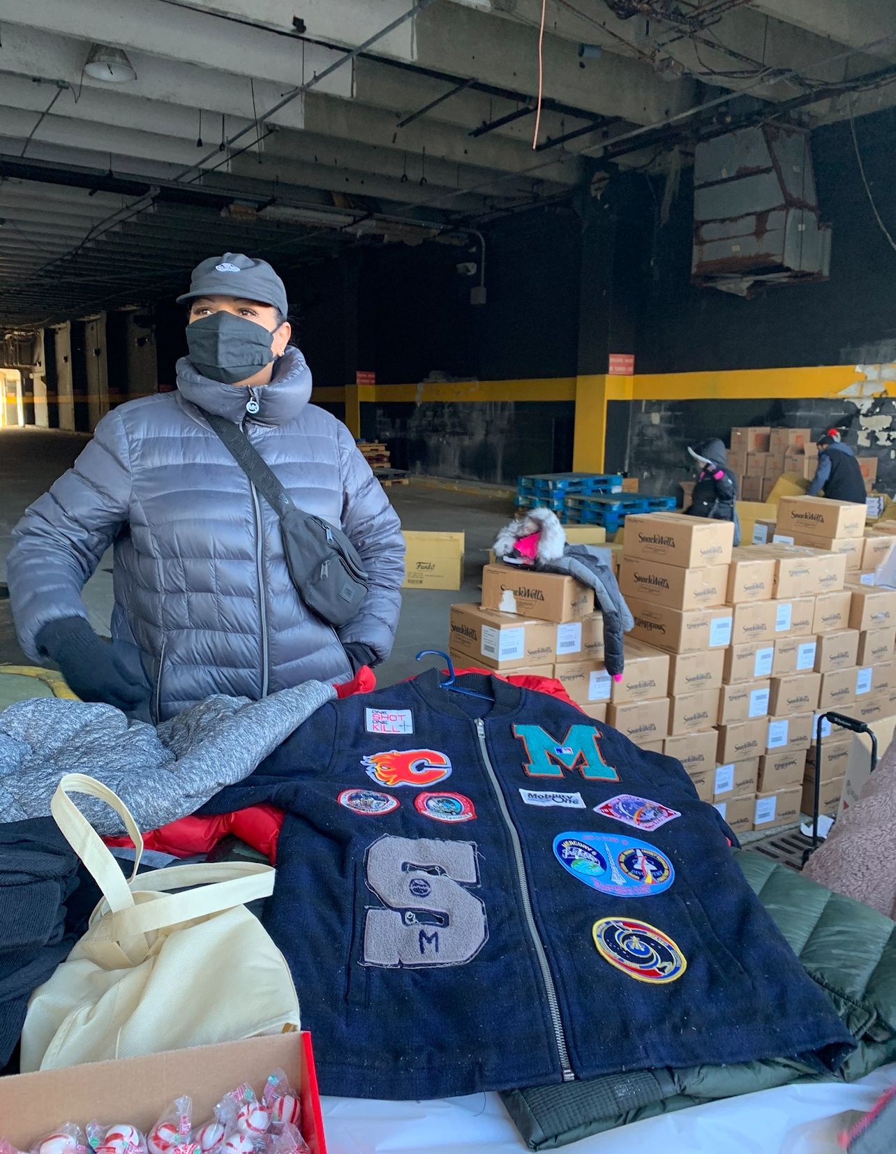 A man wearing a mask is standing in front of a pile of clothes.