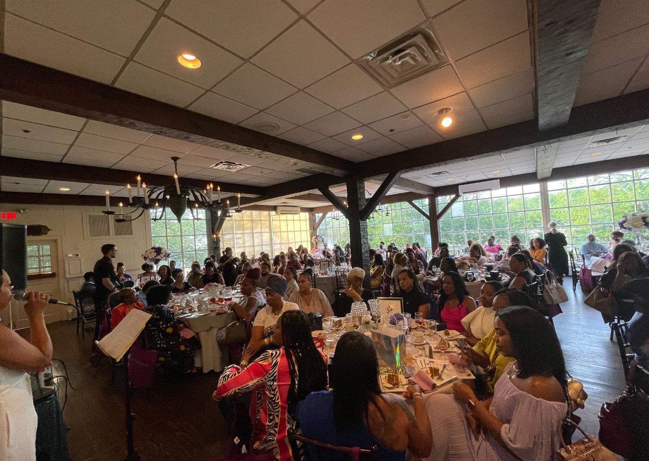 A large group of people are sitting at tables in a large room.