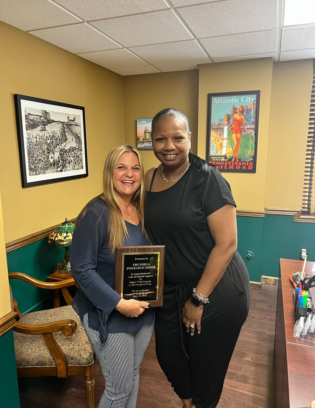 Two women are standing next to each other in a room holding a plaque.