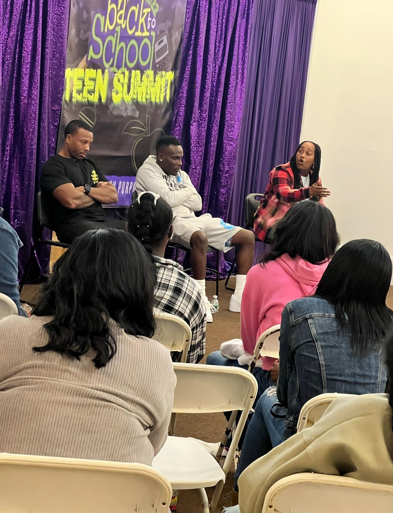 A group of people are sitting in chairs in front of a stage.