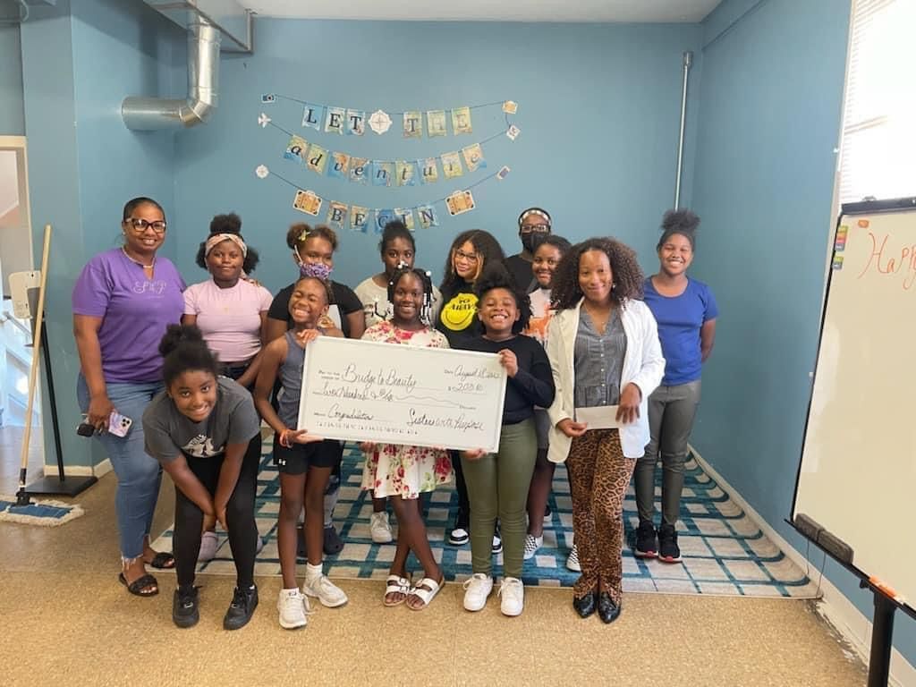 A group of young girls are posing for a picture while holding a check.