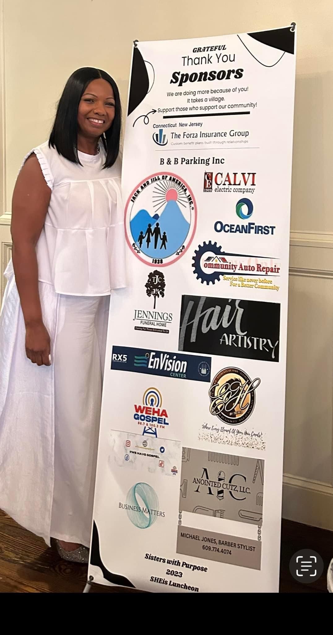 A woman in a white dress is standing next to a banner with logos on it.