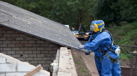 Two men in protective suits are working on a roof.