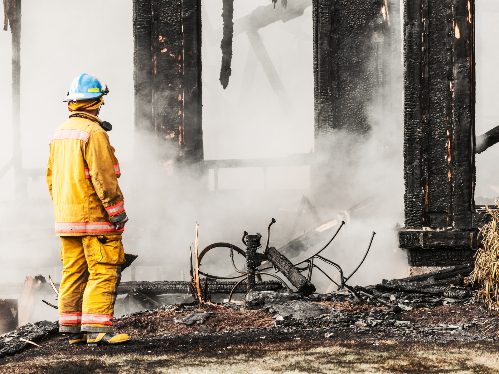 Fire fighter taking checking for heat spots post burning building. 