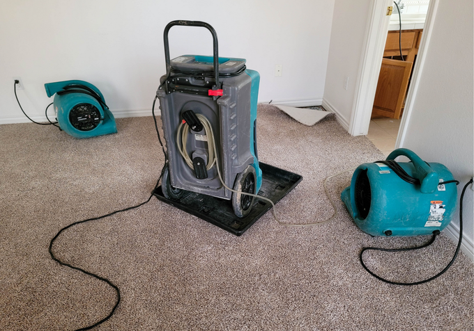 A room with a vacuum cleaner and a dryer on the floor.