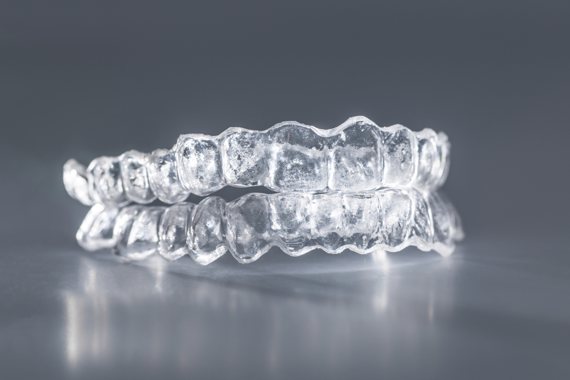 a pair of clear plastic teeth aligners on a gray surface