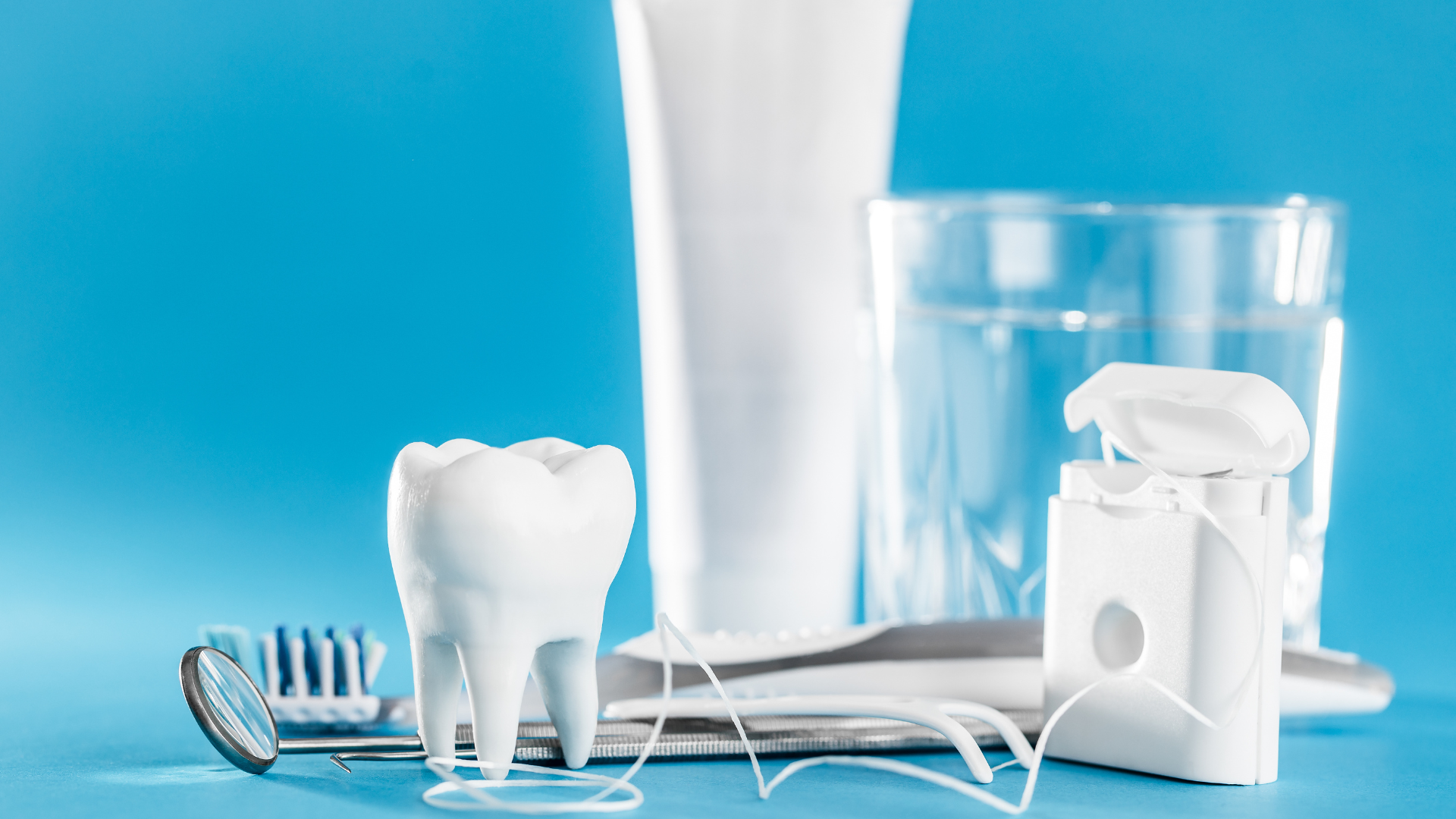 a tooth , toothbrush , toothpaste , floss , and a glass of water on a blue background .