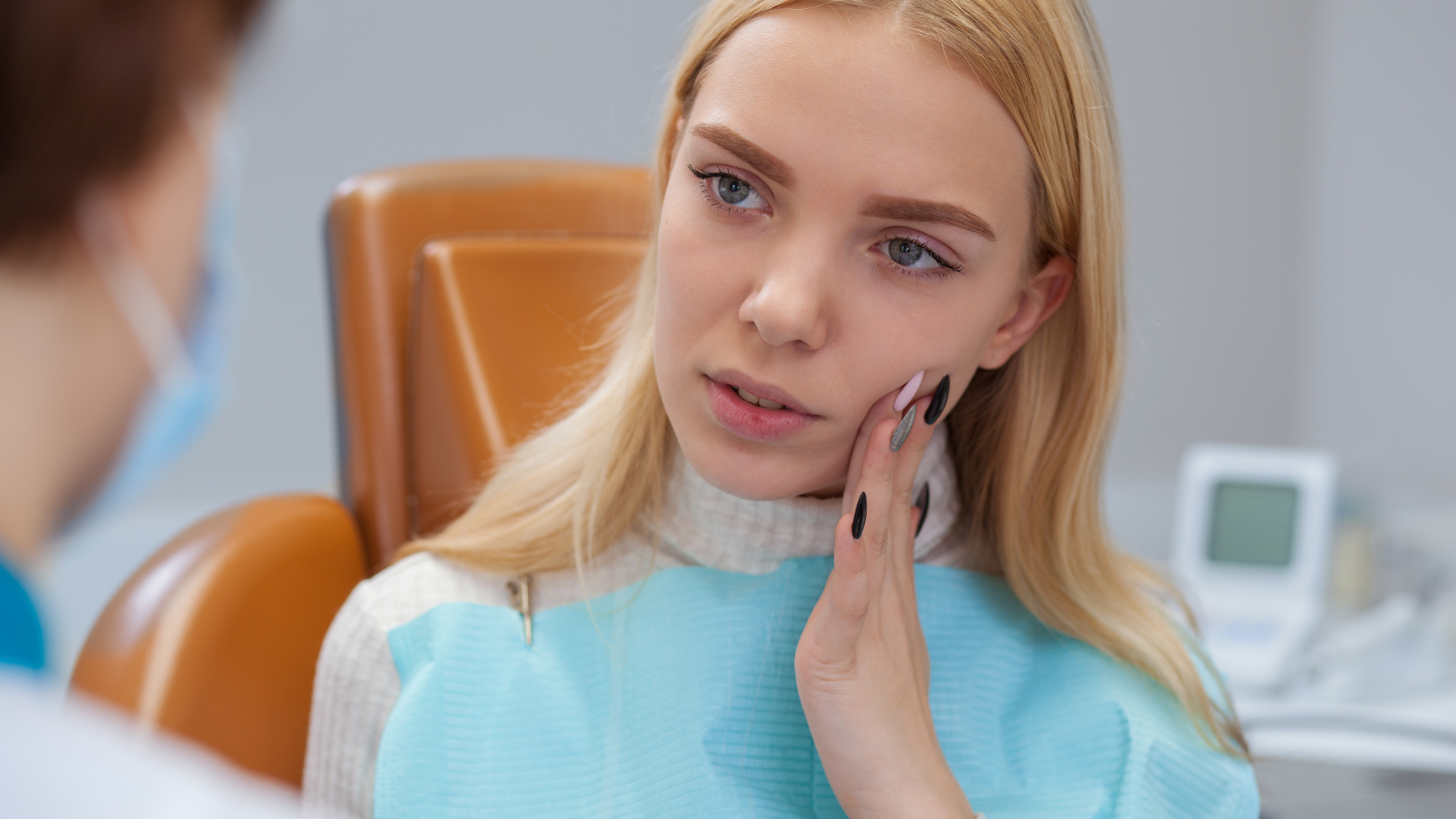 A woman is sitting in a dental chair with a toothache.