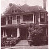 a black and white photo of a large house with a porch .