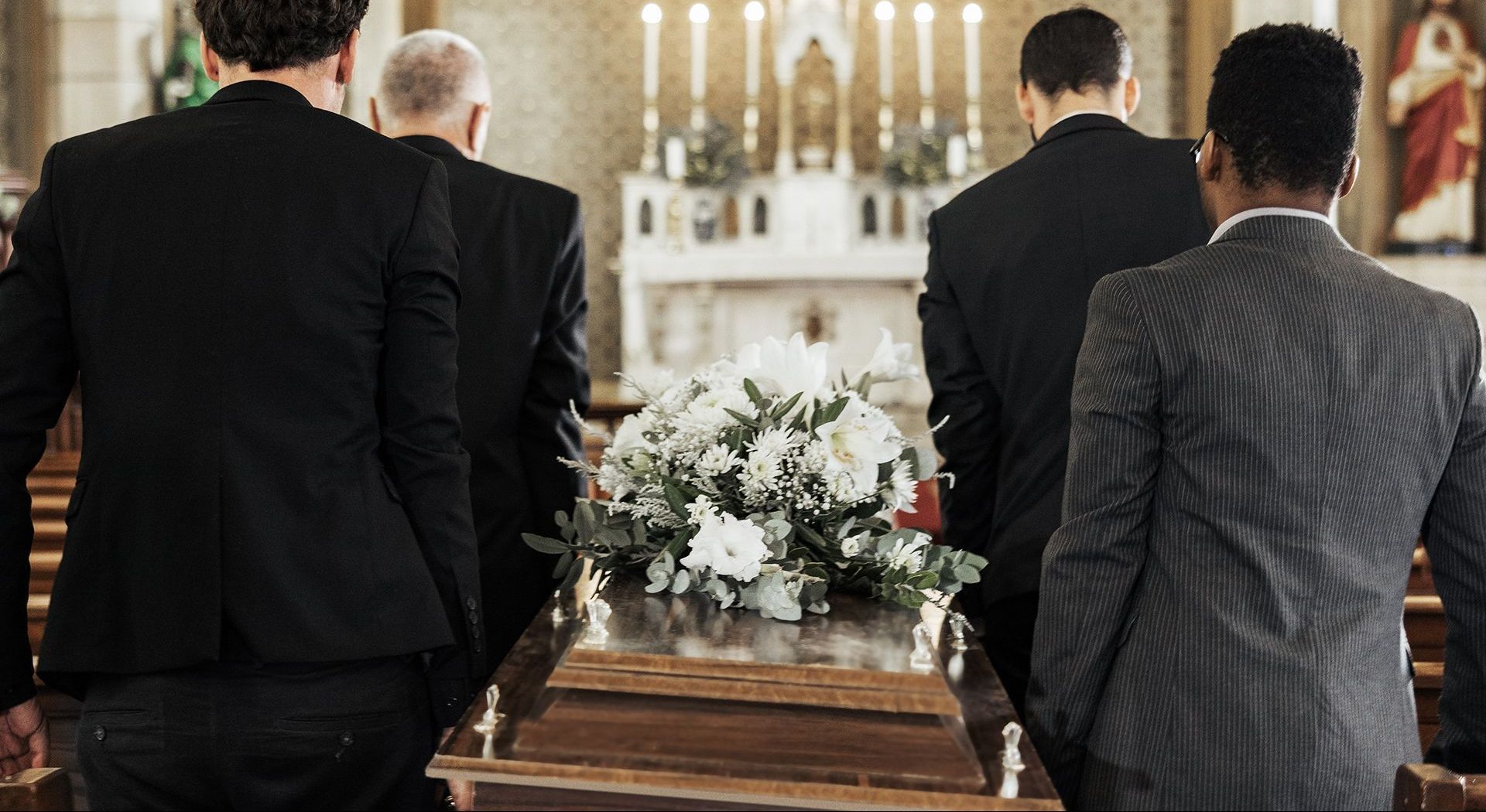 A group of men in suits are carrying a coffin in a church.