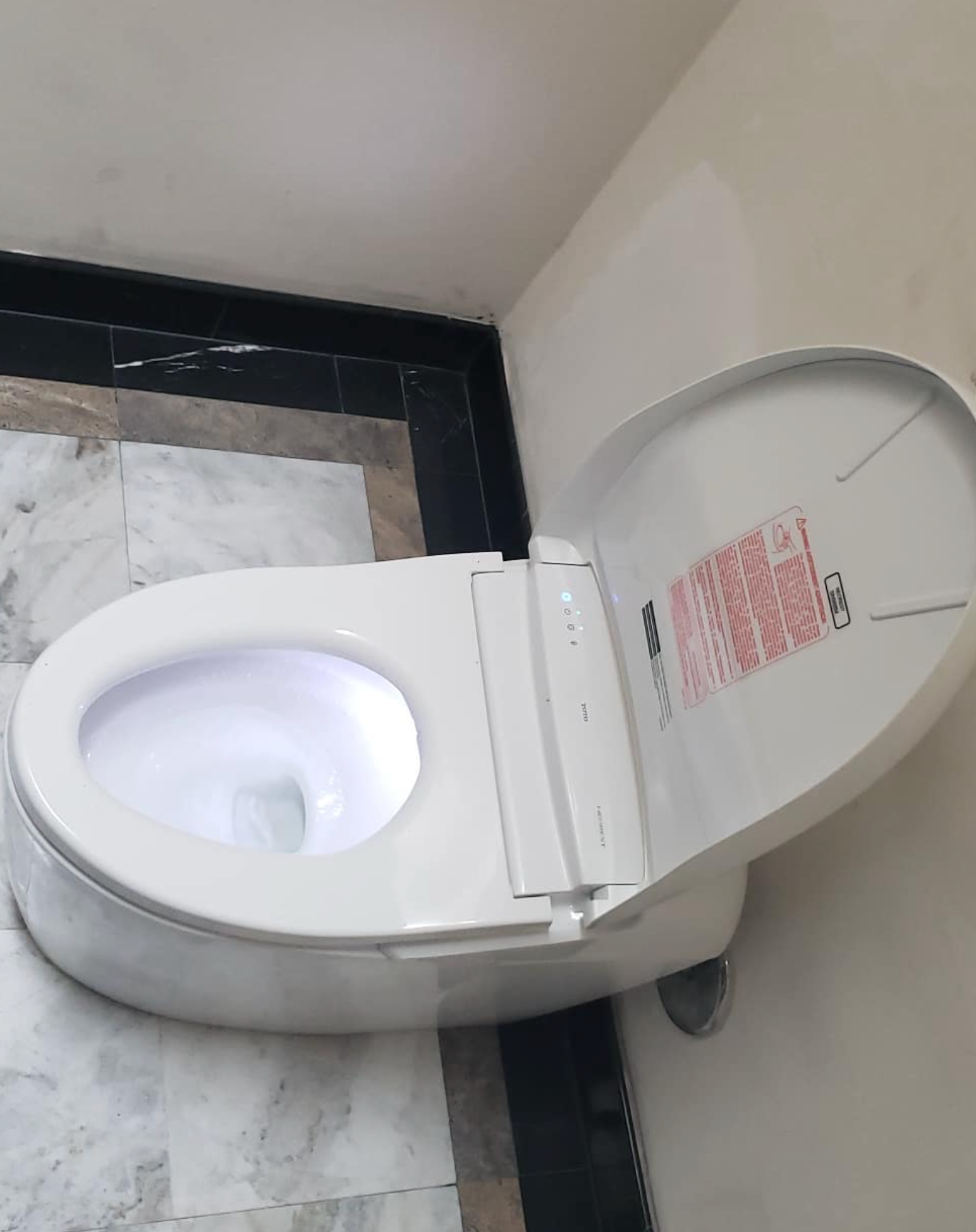 A white toilet with the lid open in a bathroom.