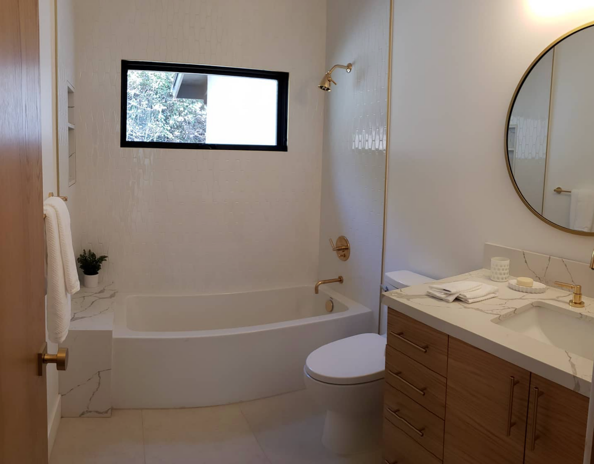 A bathroom with a tub , toilet , sink and mirror.