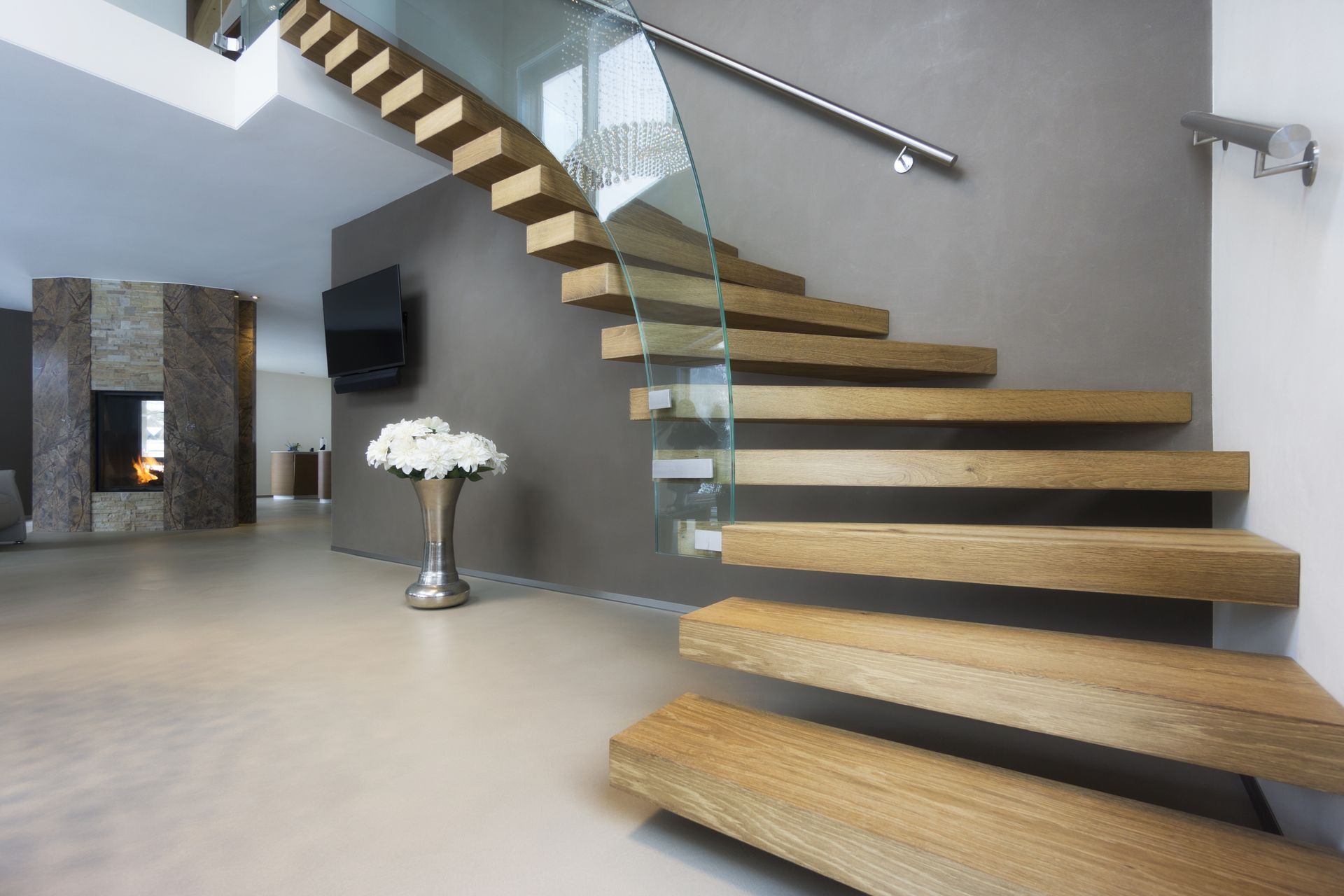 A wooden staircase with a glass railing in a house