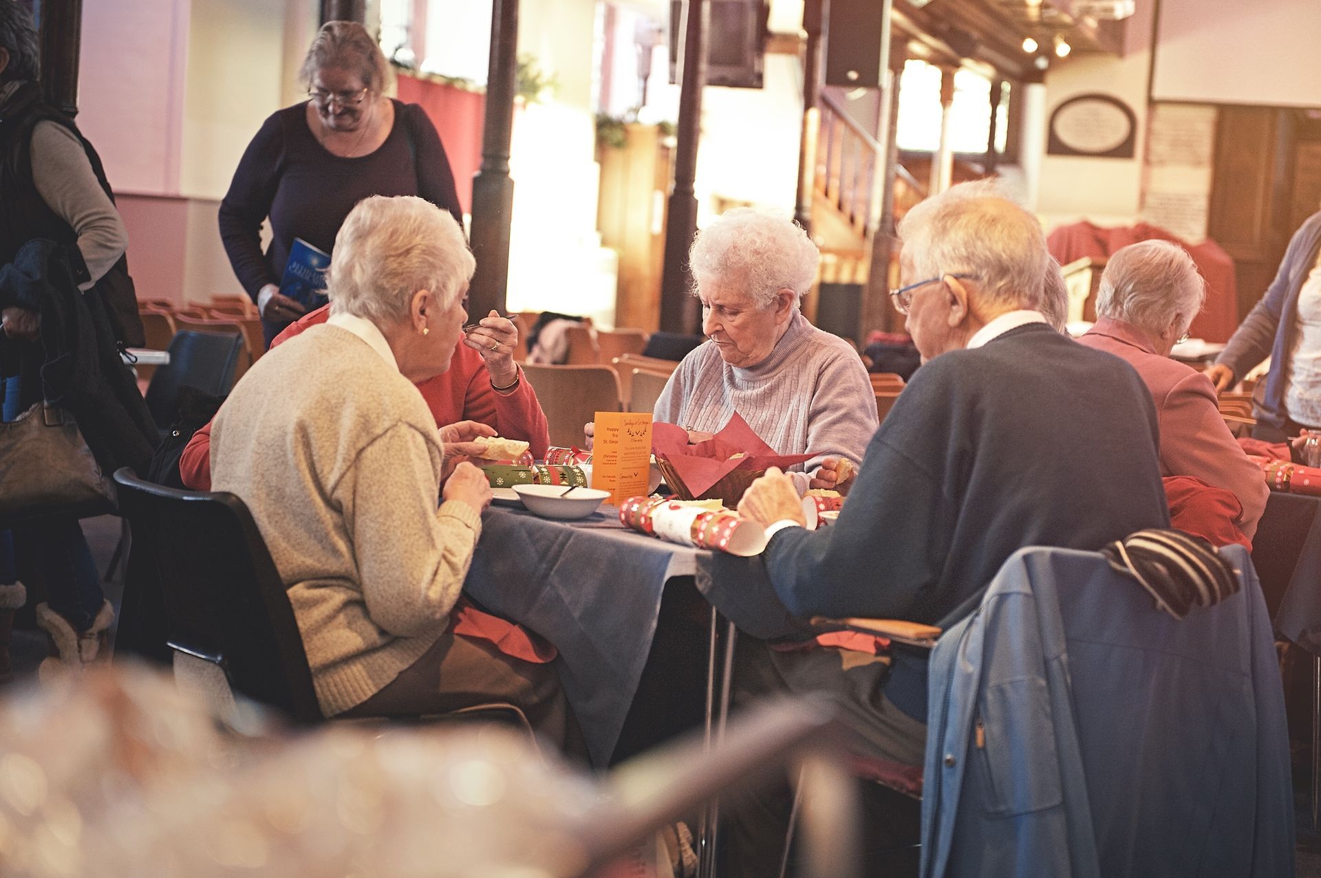 People seated at a café table, talking and eating in a warm indoor setting
