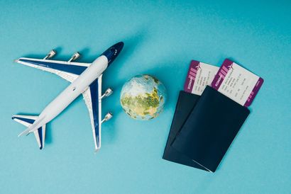Passport, boarding passes, toy airplane, and small globe on a blue background