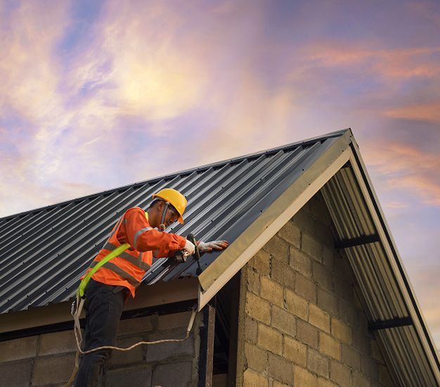 Gray tiled roof of a building; scaffolding at left, windows in background, cloudy sky.