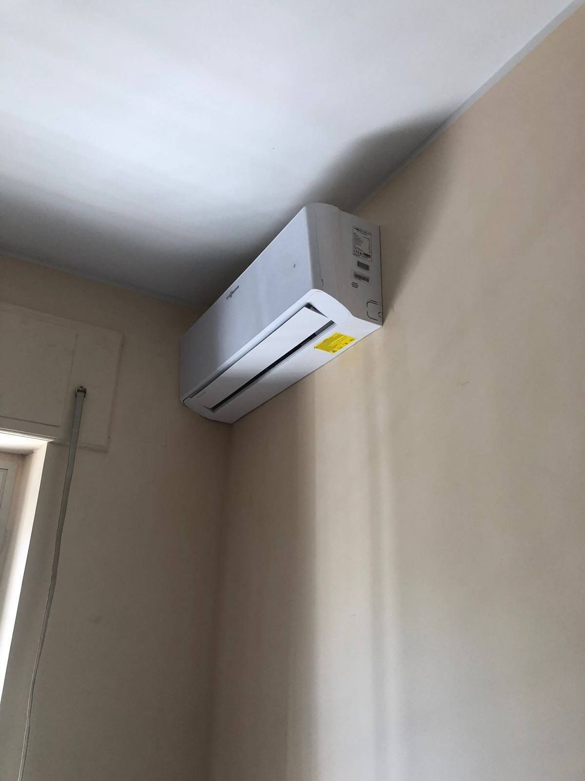 In una stanza è appeso al soffitto un condizionatore bianco.