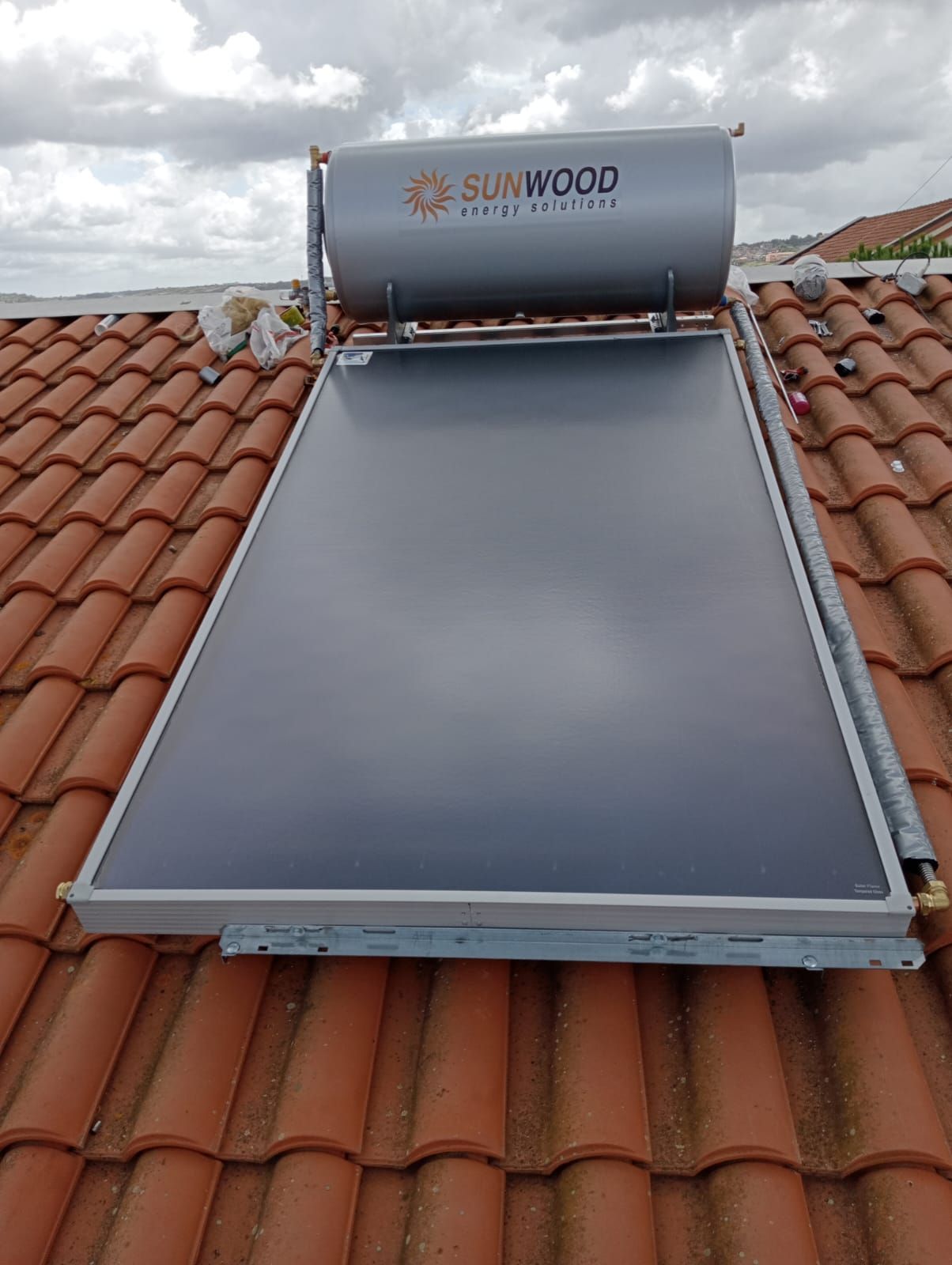 Uno scaldabagno solare è posizionato sopra un tetto di tegole.