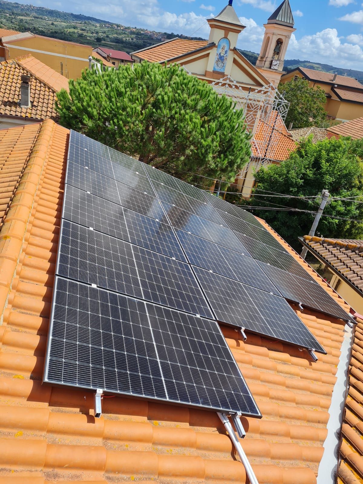 Una fila di pannelli solari è posizionata sopra un tetto di tegole.