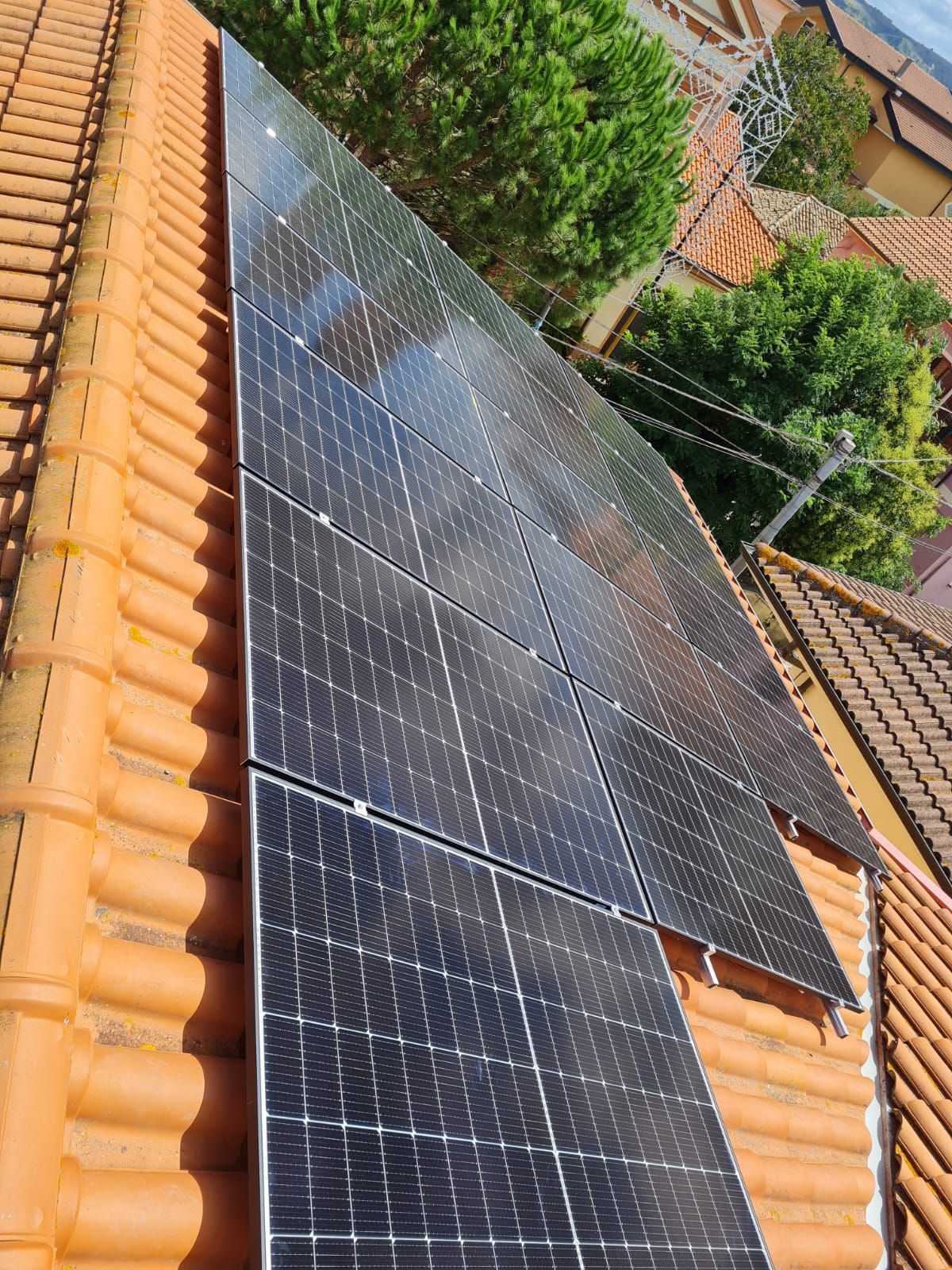 Una fila di pannelli solari posizionati sopra un tetto di tegole.