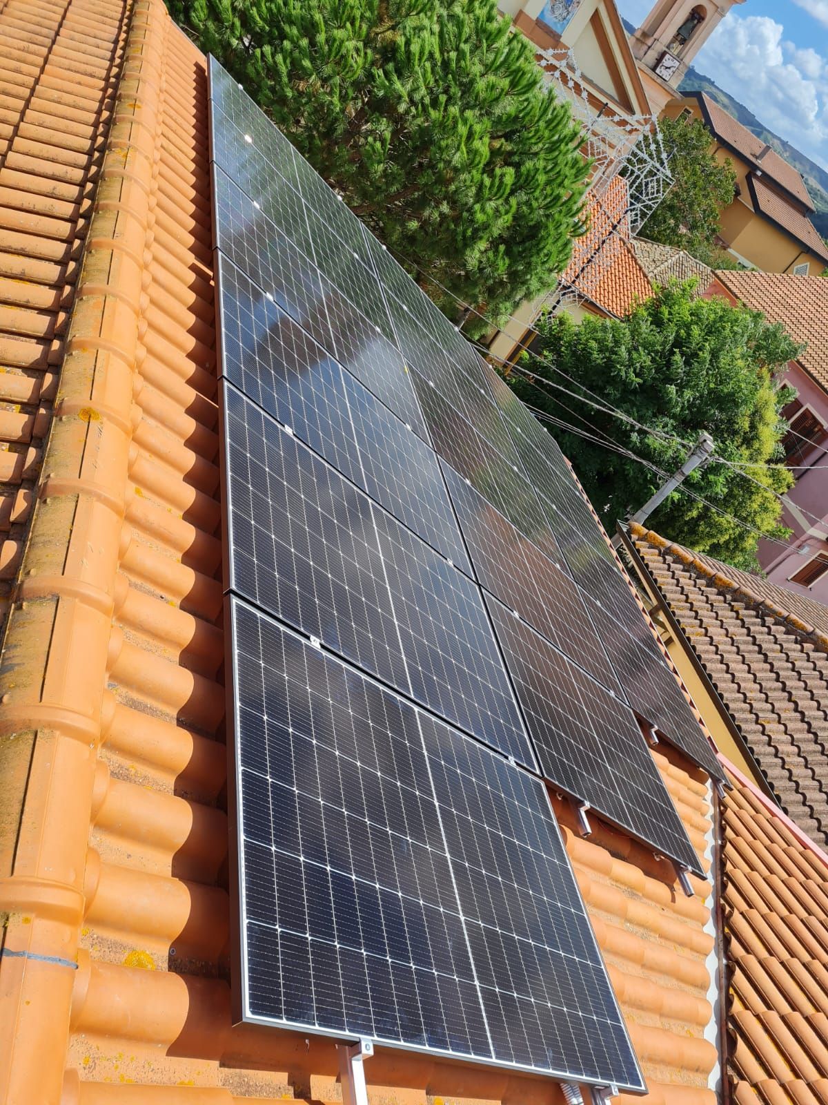 Una fila di pannelli solari posizionati sopra un tetto di tegole.