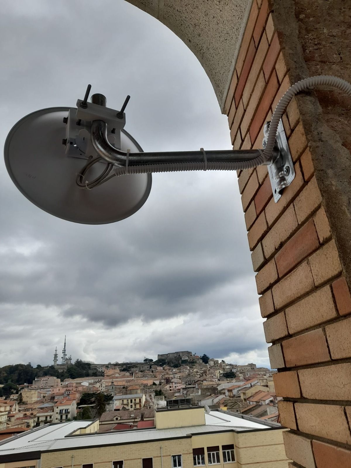 Una parabola satellitare è fissata a un muro di mattoni.