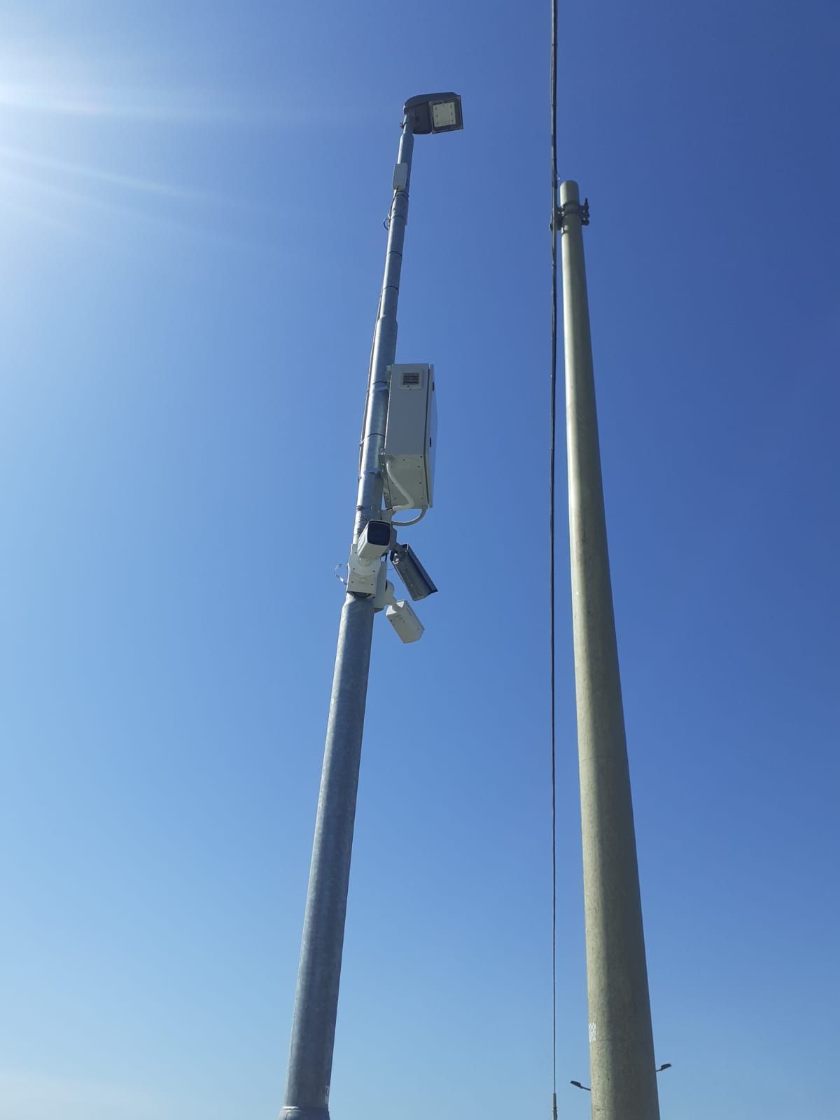 Un palo con una telecamera attaccata contro un cielo azzurro