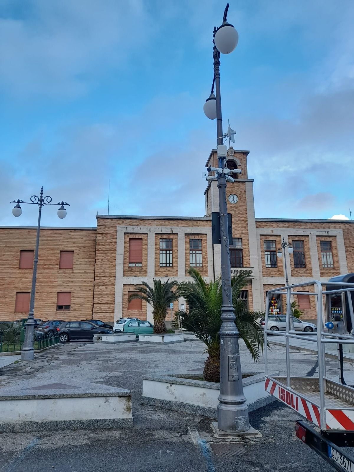 Un edificio in mattoni con una torre dell'orologio e un lampione di fronte