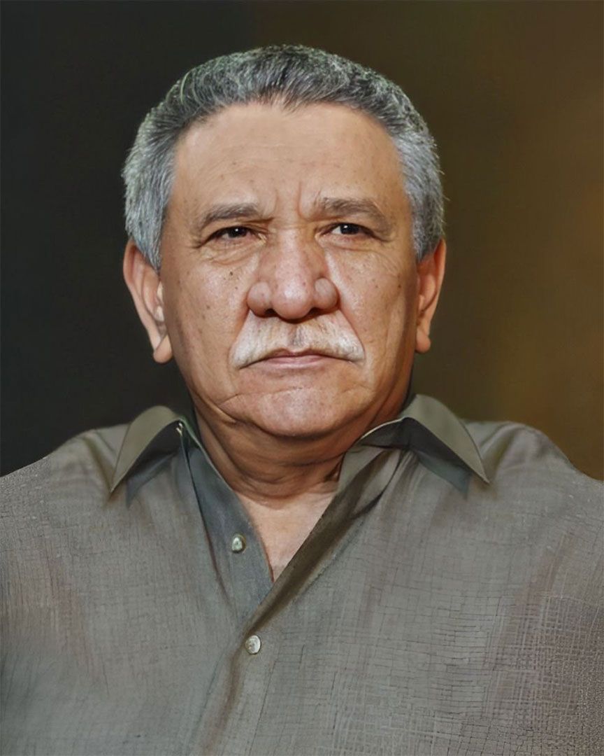 A man with a mustache is wearing a grey shirt