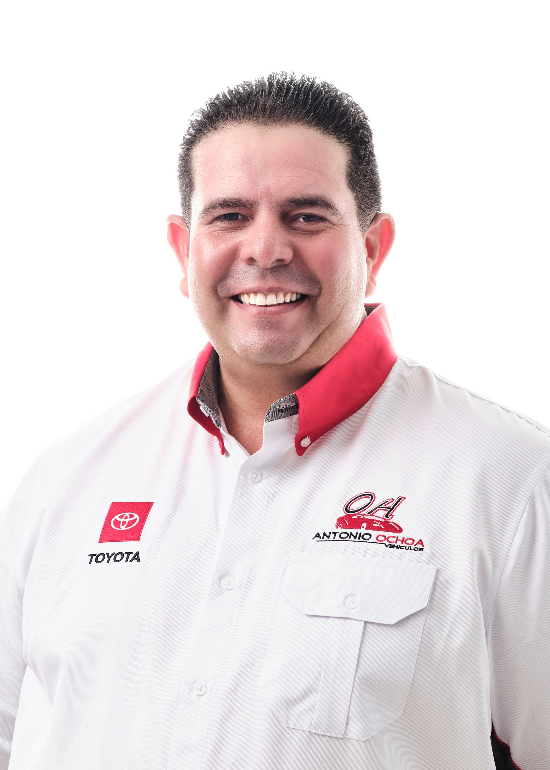 A man in a white shirt with a red collar is smiling.