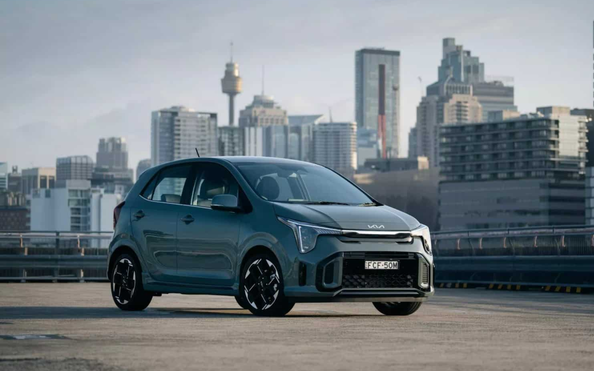 A car is parked in a parking lot in front of a city skyline.