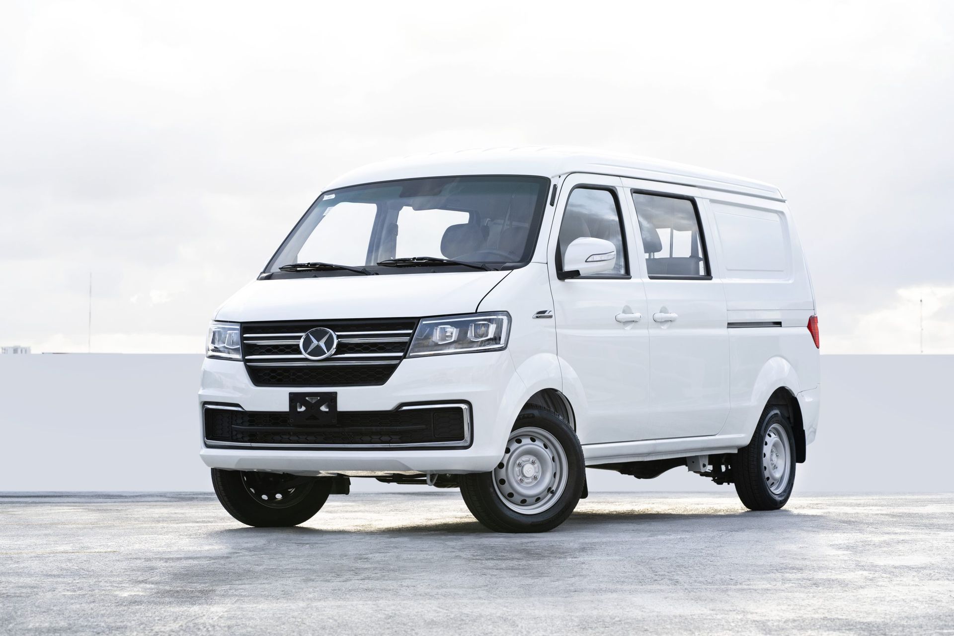 A white van is parked in front of a white wall.
