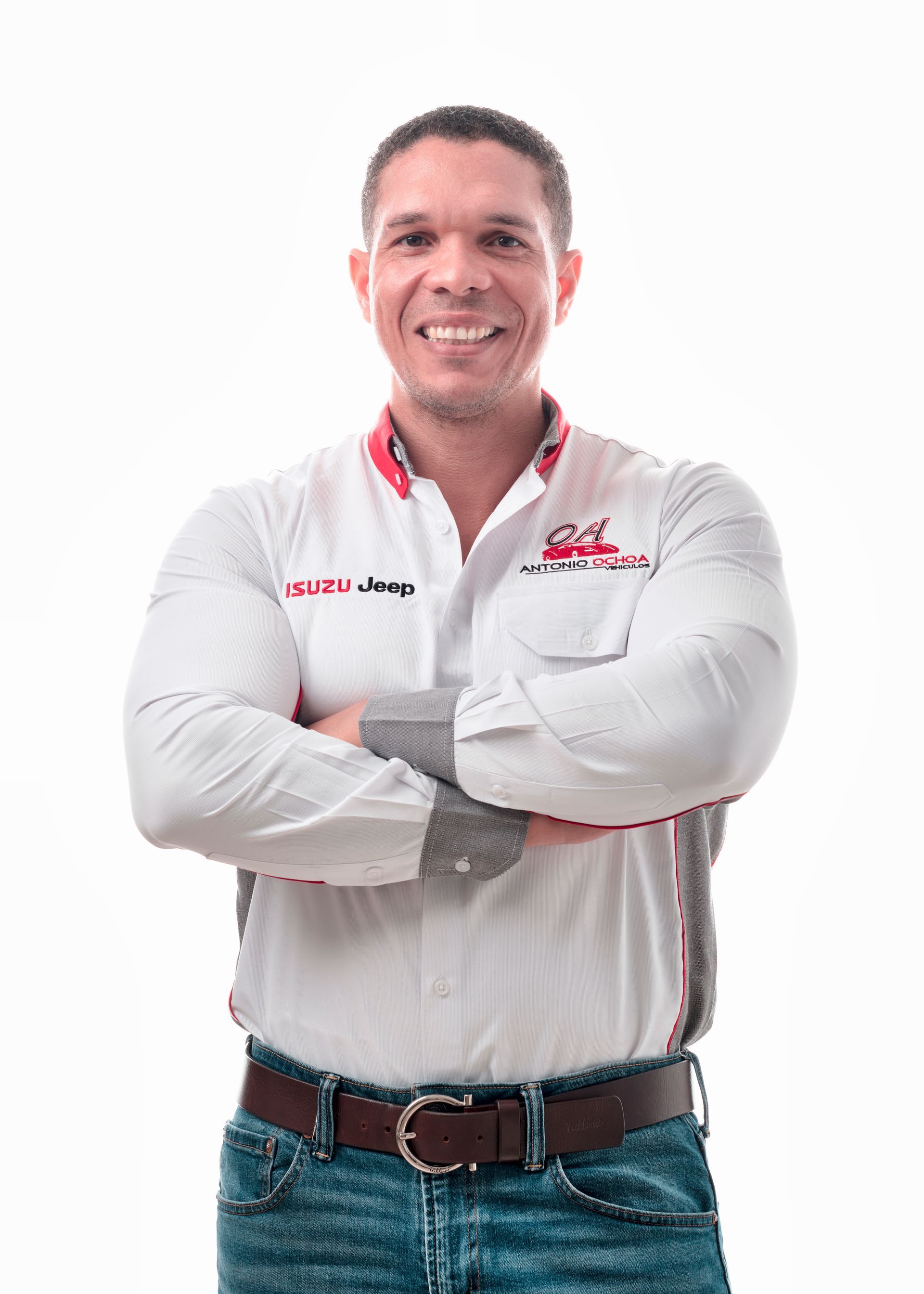 A man in a white shirt and blue jeans is standing with his arms crossed.