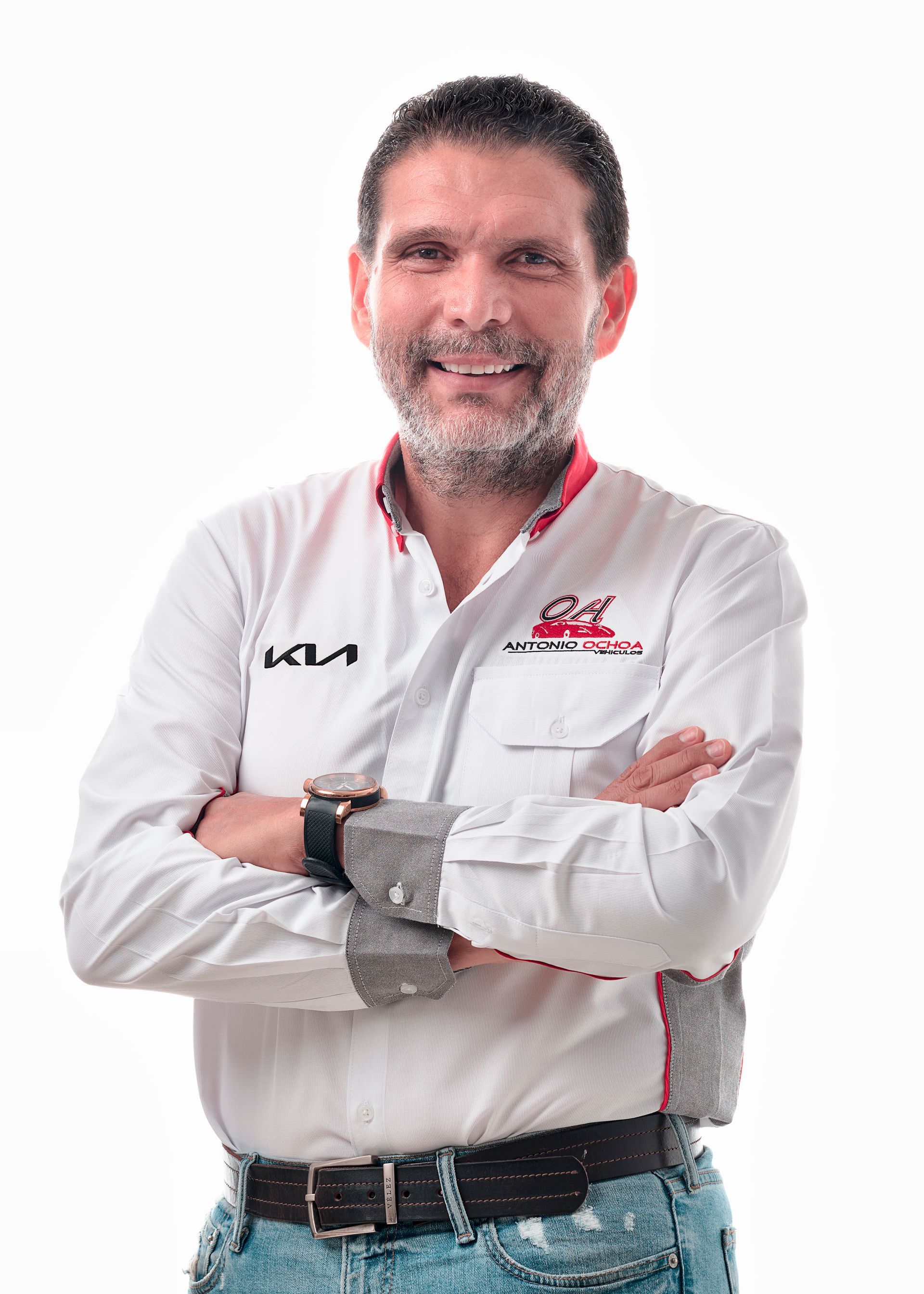 A man with a beard is standing with his arms crossed and smiling.