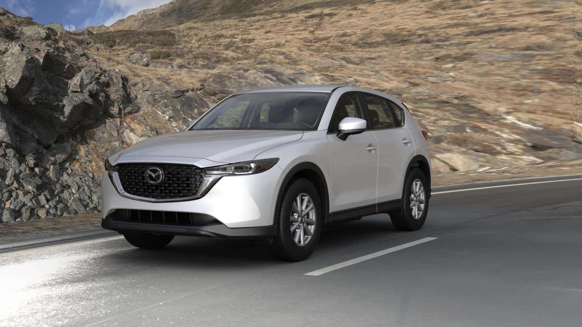 A white mazda cx-5 is driving down a mountain road.