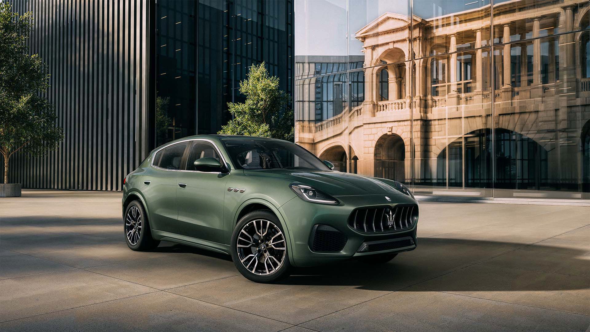 A green maserati is parked in front of a building.