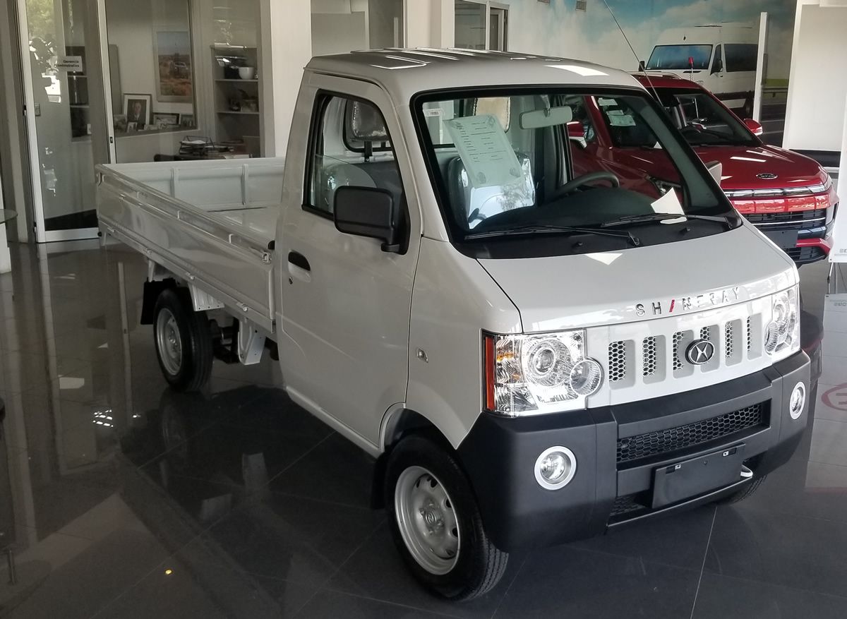 A small white truck is parked in a showroom.