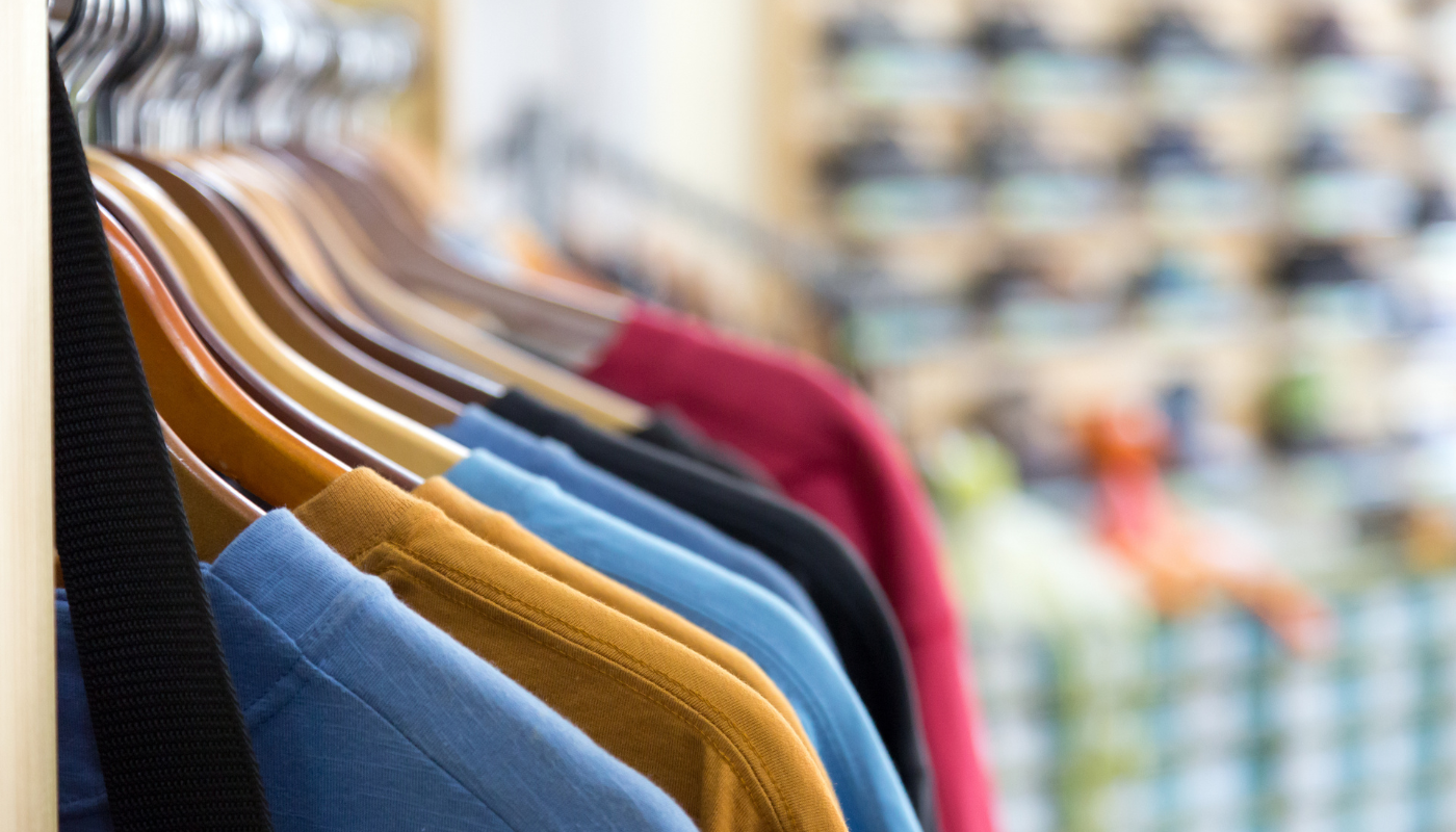 Clothes hanging on a rack; shirts in various colors, blurred background of more items.