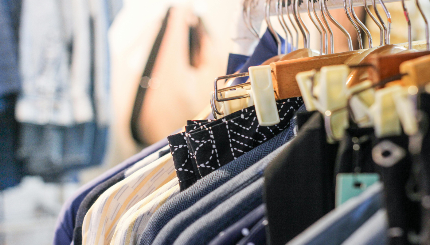 Clothing on hangers in a shop, mostly blues and whites.