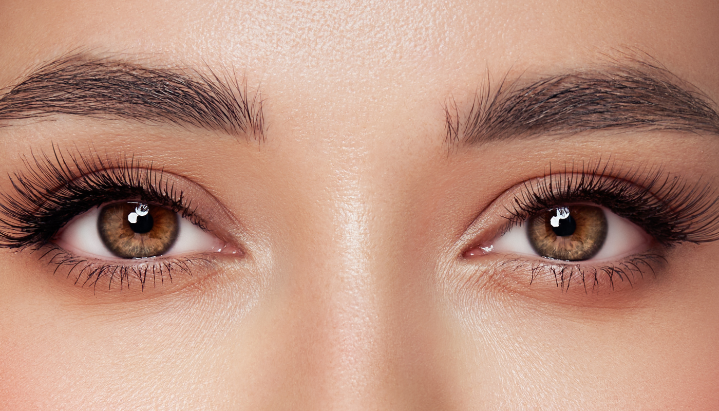 Close-up of two brown eyes with thick eyelashes and full, dark eyebrows.