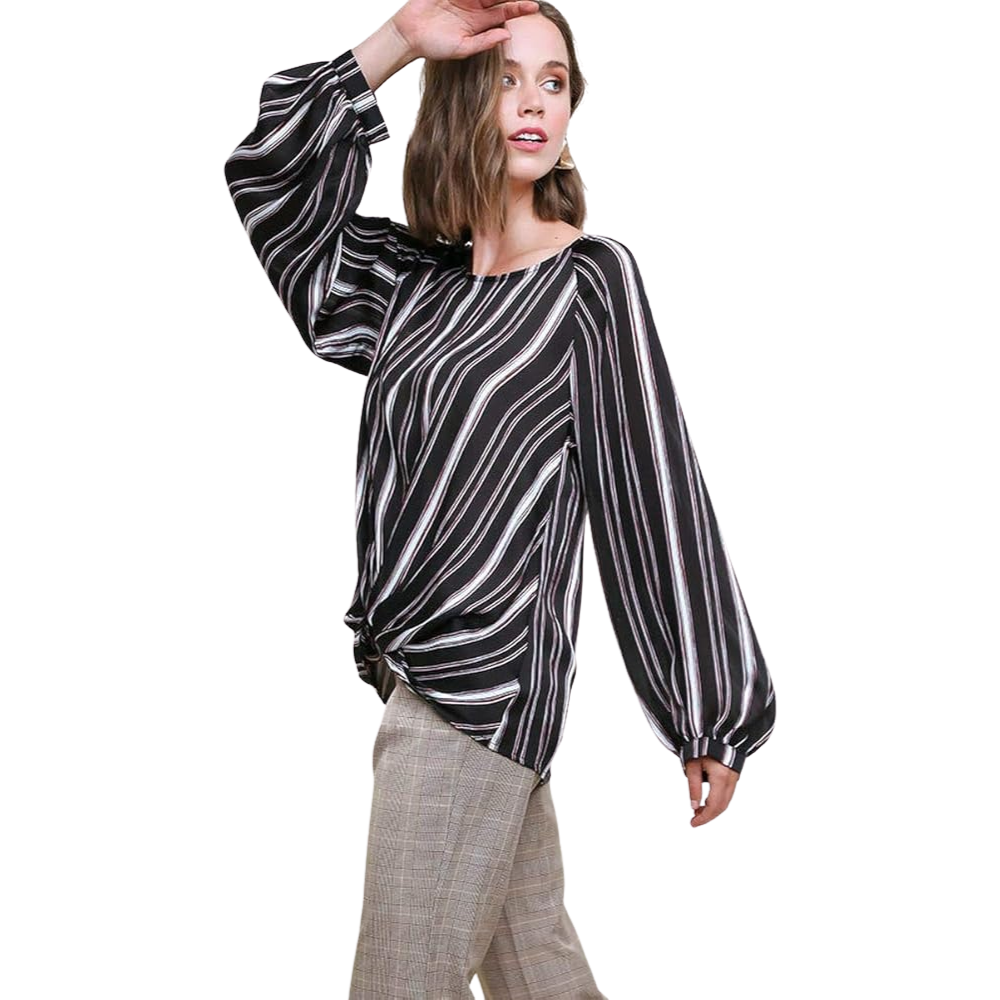 Woman in black and white striped top with balloon sleeves, hand raised, brown pants.