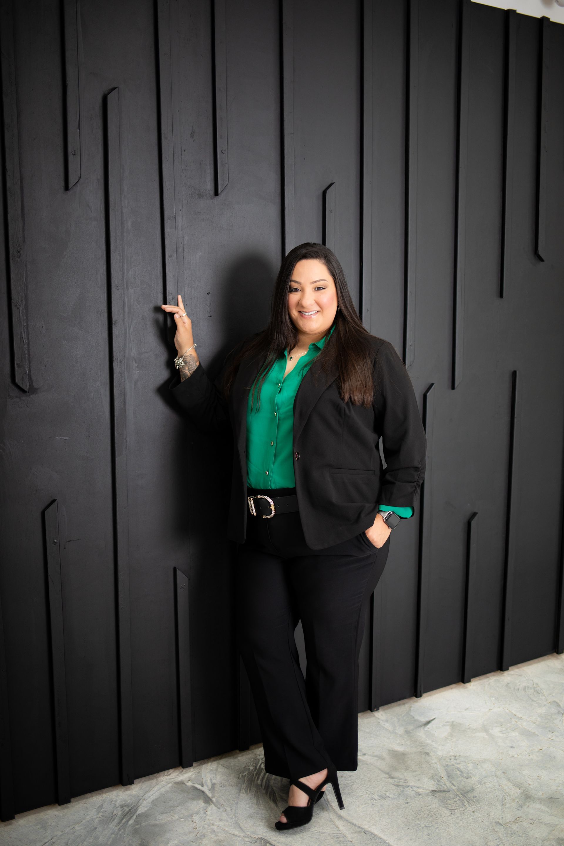A woman is sitting at a desk with a laptop and a vase of flowers.