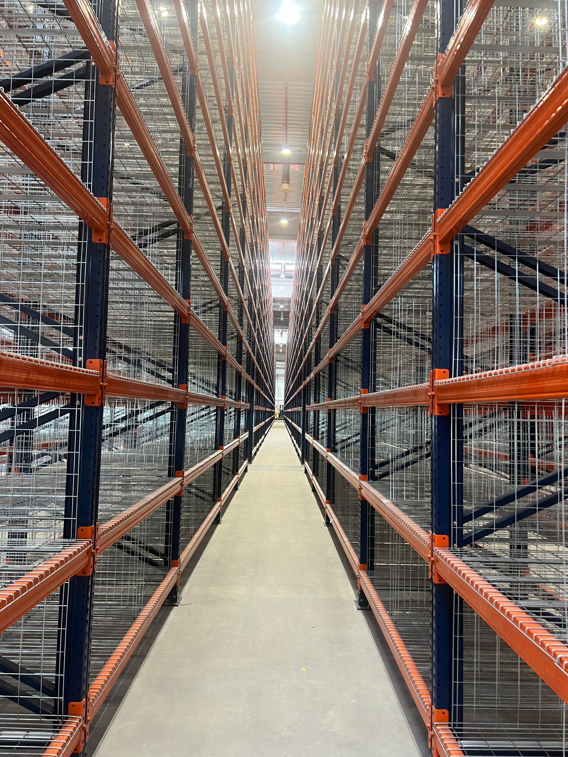 Un magazzino con molti scaffali e una passerella tra di loro.