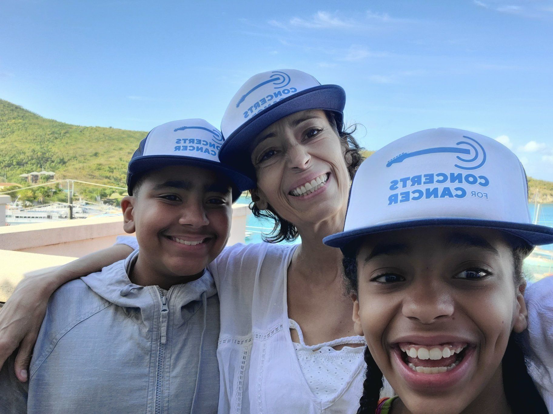 A woman and two children wearing baseball caps are posing for a picture.