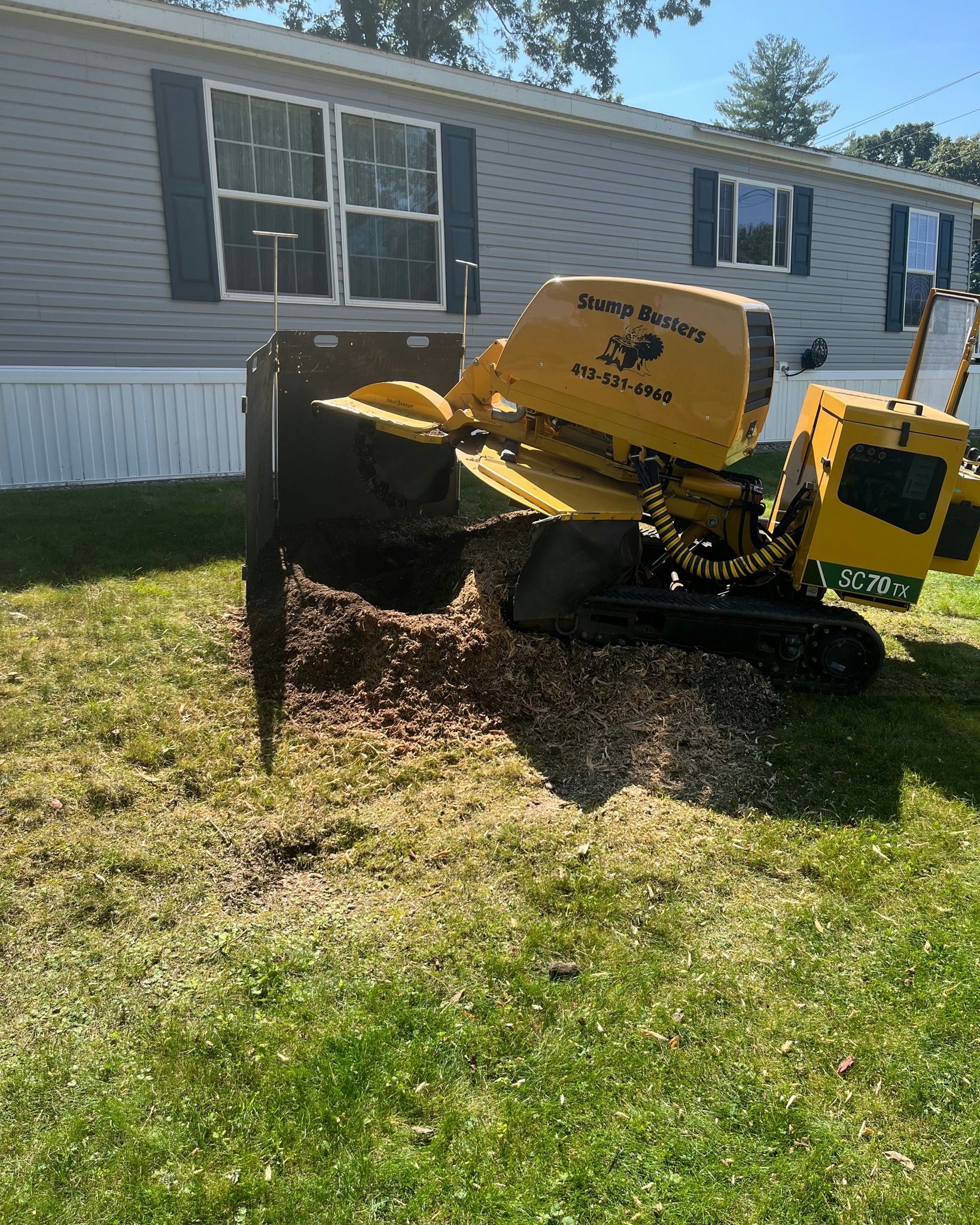 Yellow stump grinder in front yard grinding a tree stump.