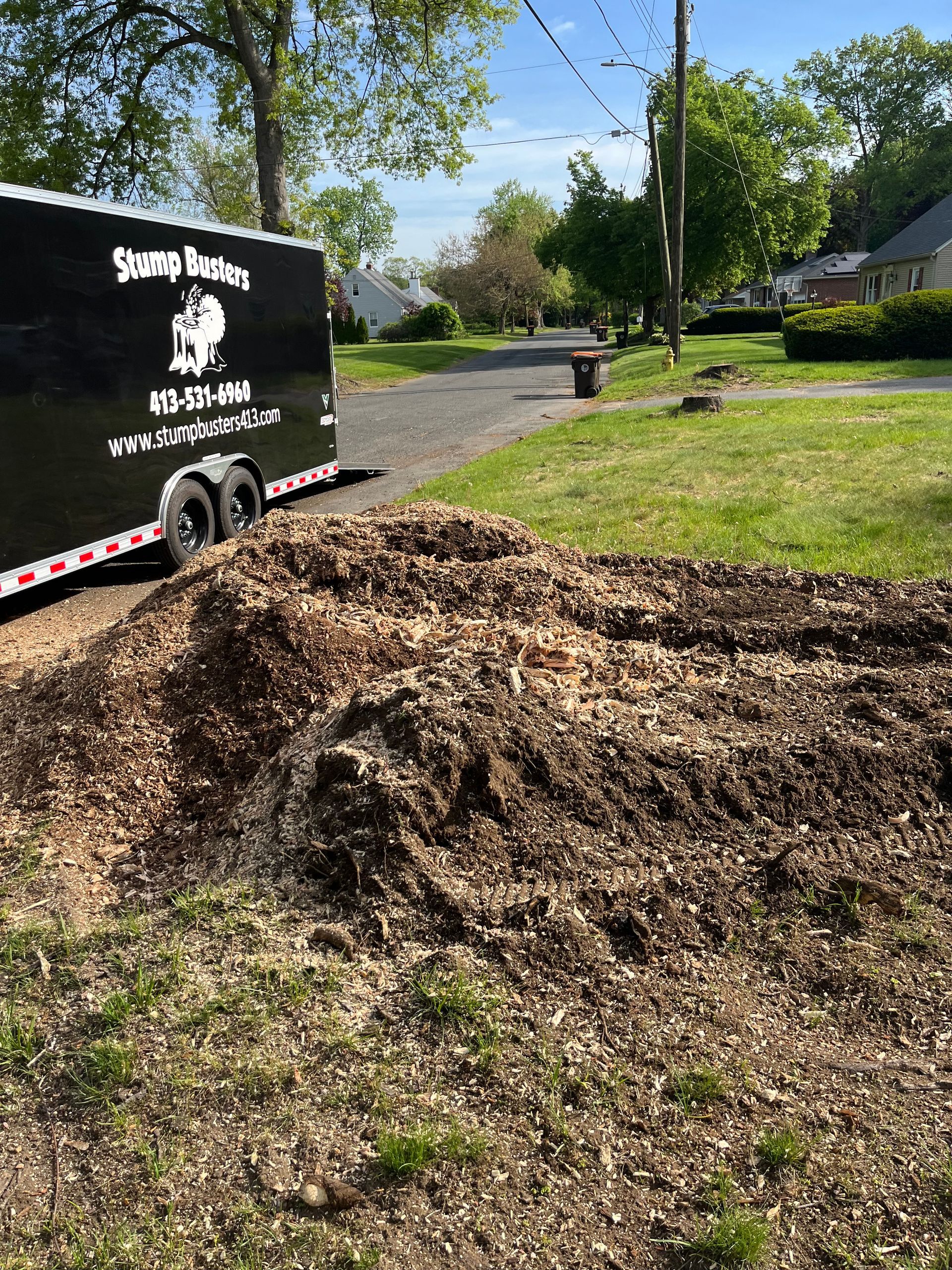 Large pile of wood chips next to a black trailer labeled 