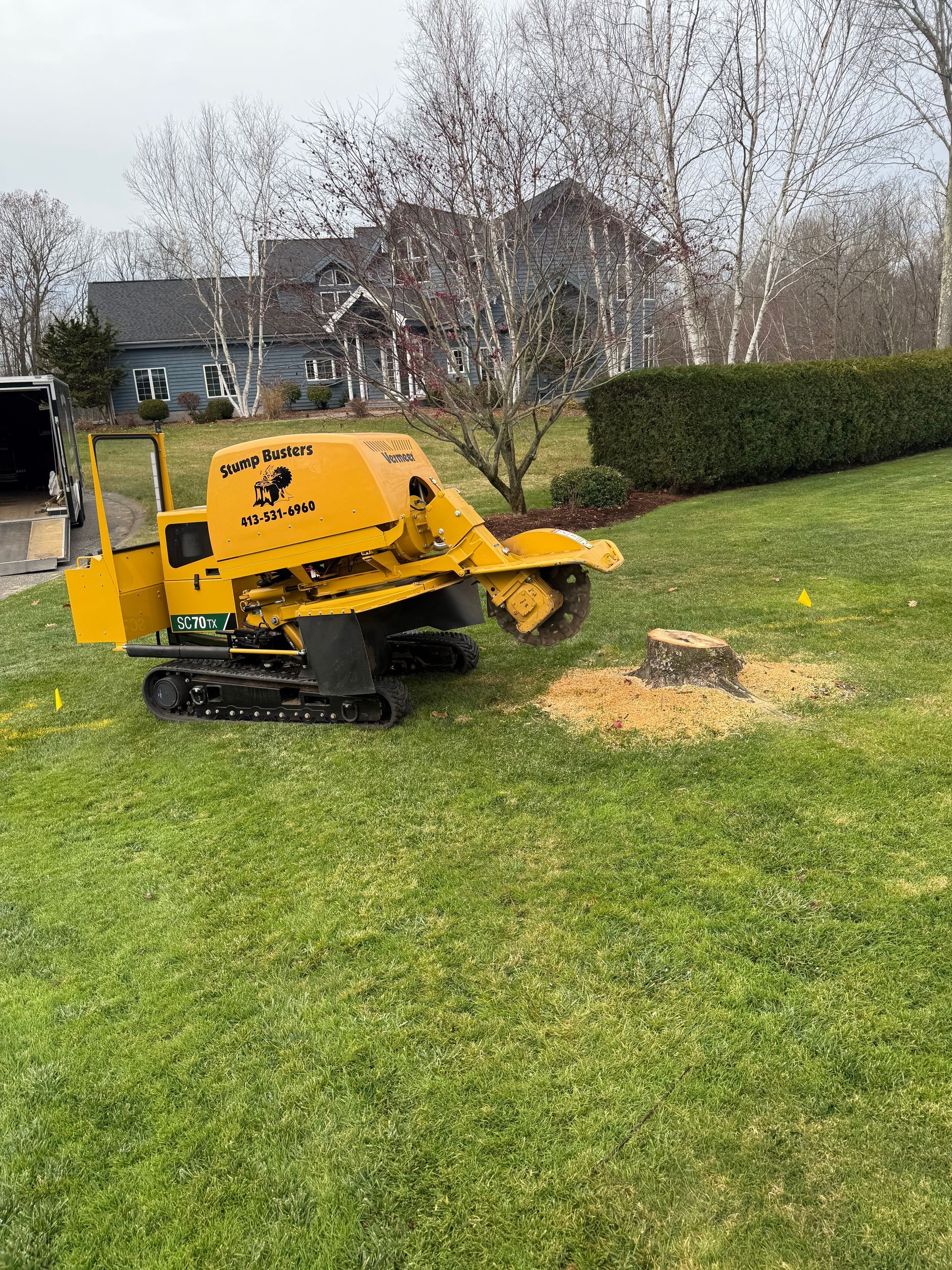 Yellow stump grinder on a lawn grinding a tree stump. Green grass, residential setting.