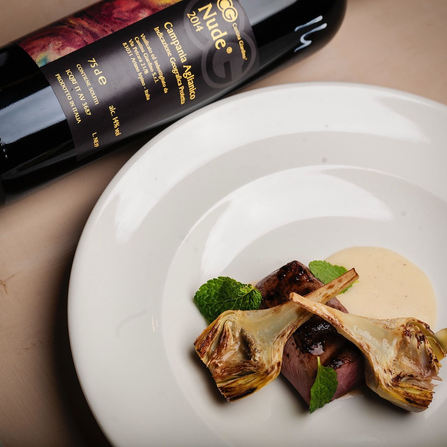 Una bottiglia di vino Alude è appoggiata accanto a un piatto di cibo