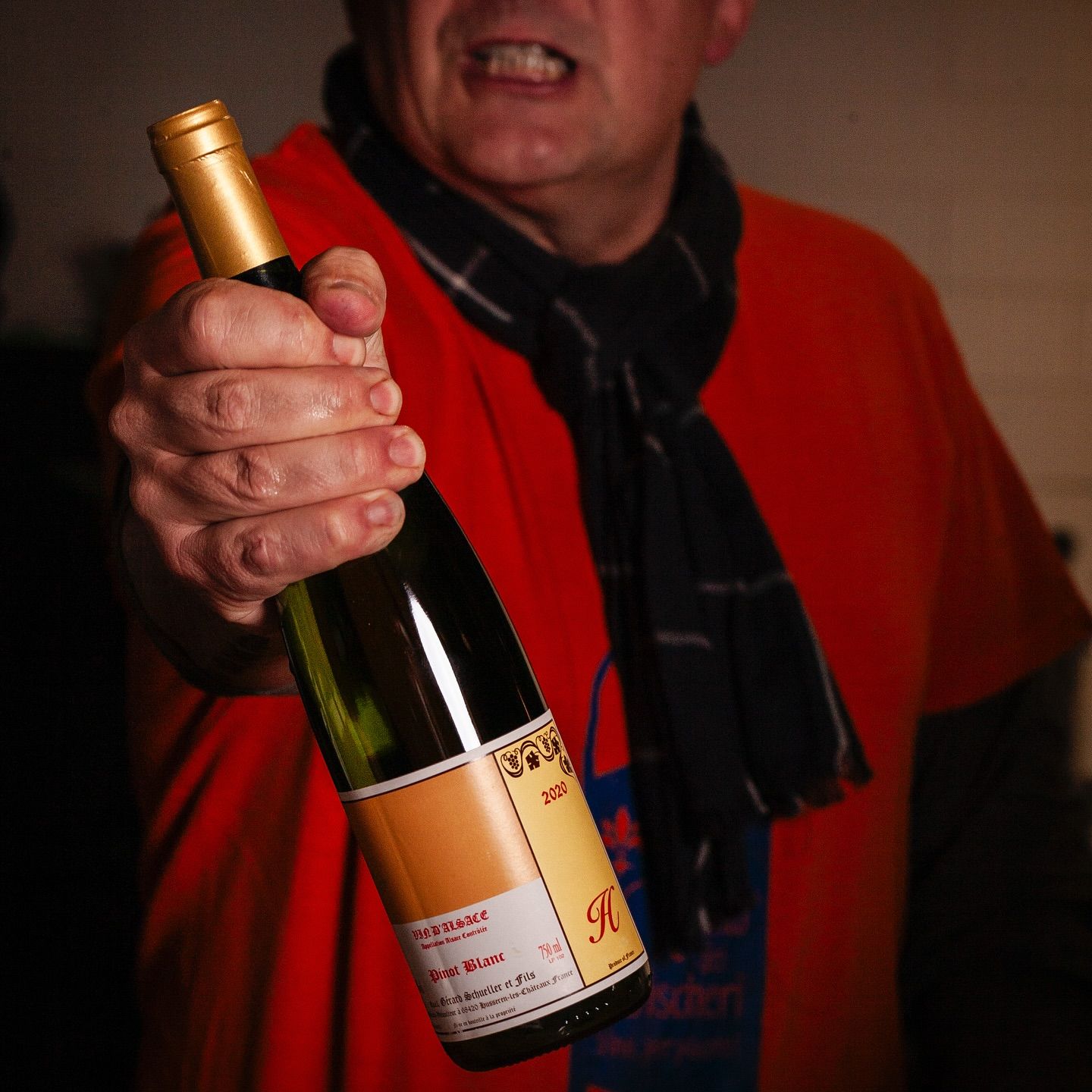 Un uomo con una camicia rossa tiene in mano una bottiglia di vino